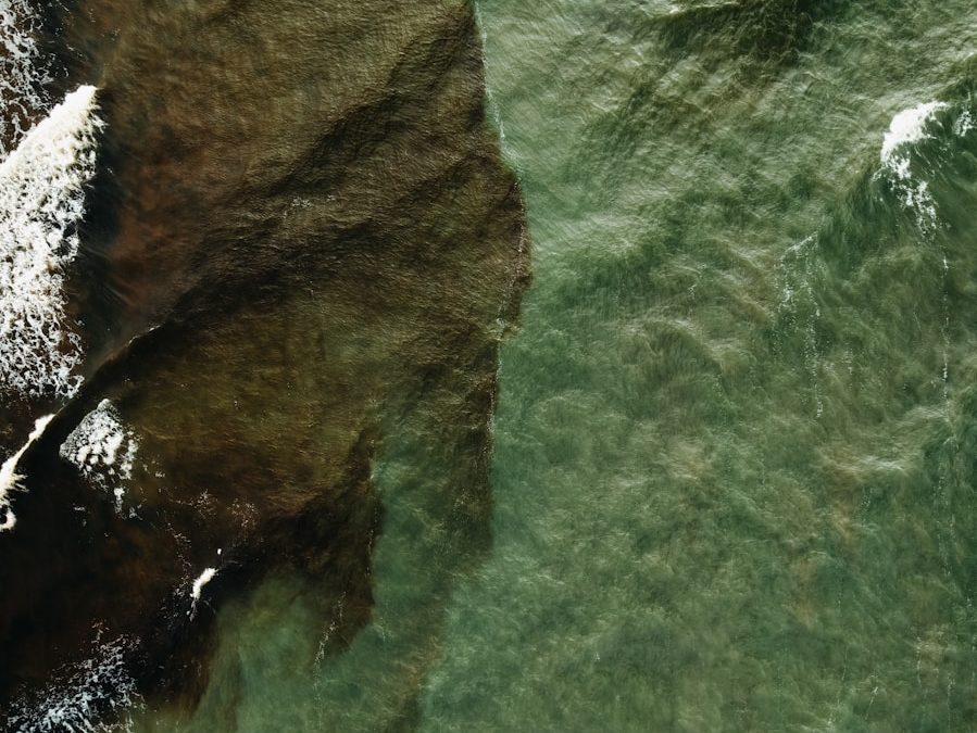Aerial view of rocky shore meeting green ocean waves