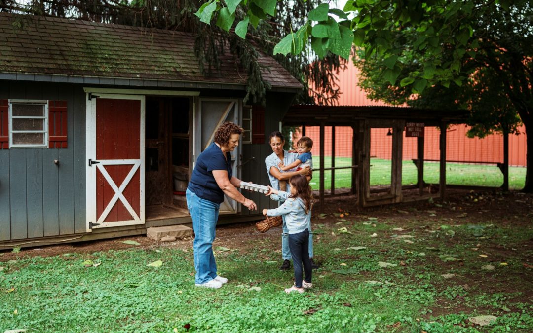 Family interacts with a woman near a shed.